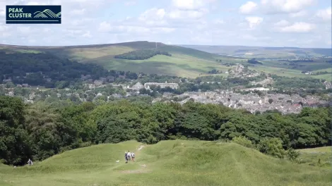 peak cluster logo in top left with a vista of rolling hills, a small town and blue skys