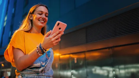 Lady walking while looking at her phone with a smile