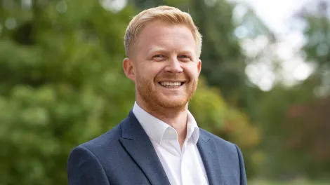 Man wearing a blue suit posing for a professional photo outside