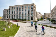 Three cyclists riding along a paved path in a modern housing area