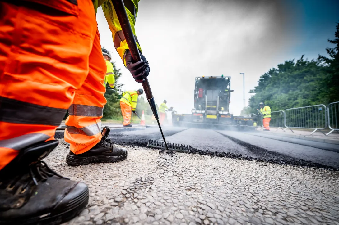 An Aggregate Industries worker uses a rake while resurfacing a road.