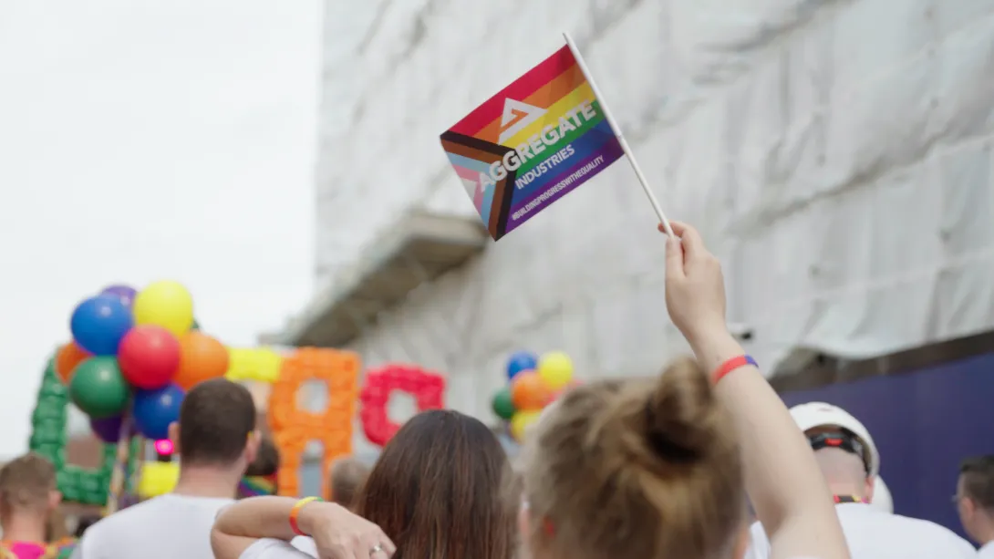 An Aggregate Industries Pride flag in rainbow colours being waved at Leicester's Pride parade in 2022