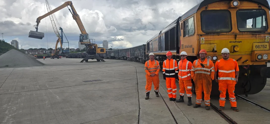 Holcim representatives with partners involved in new rail route from Bardon to Sunderland in high viz PPE in front of a freight train.