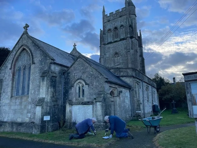 Two community volunteers planting bulbs donated by Holcim in a garden in front of a church