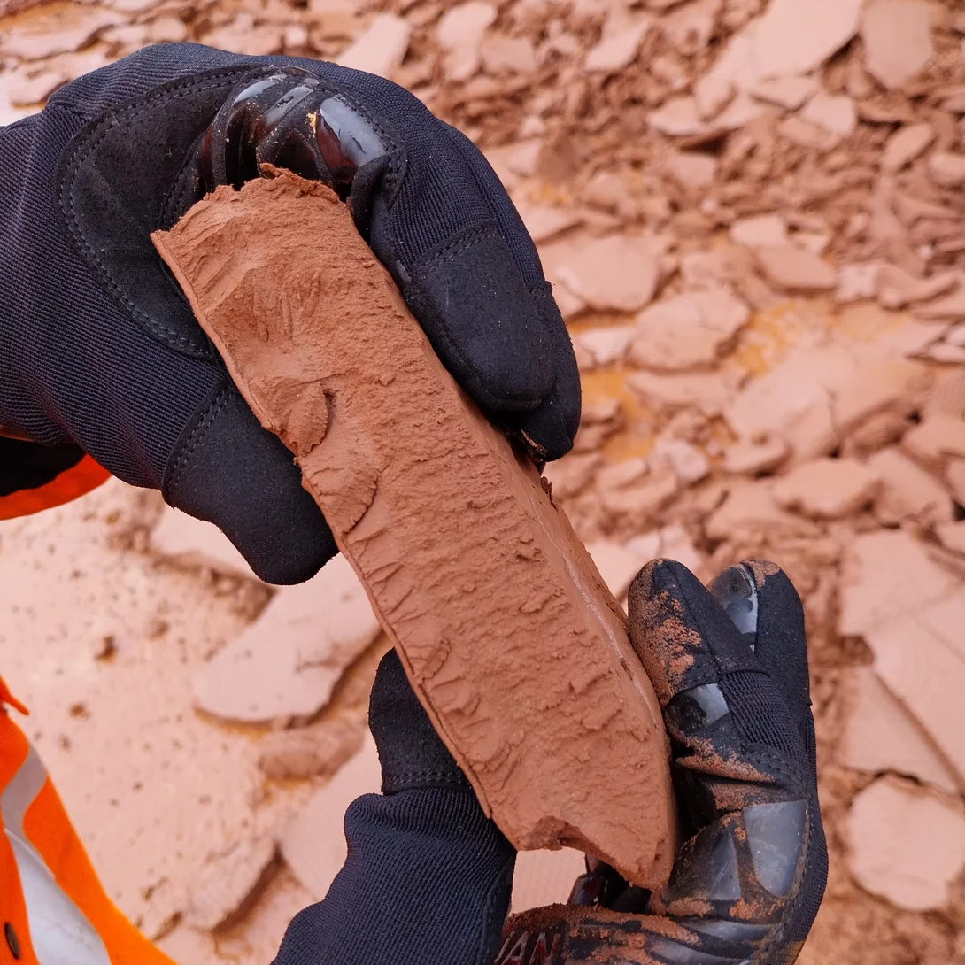 A close up of a quarry worker with gloves on holding silt cake recovered from the silt press process at Hillhead quarry.