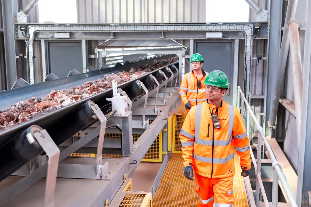 Two Holcim UK colleagues in high viz PPE looking over part of the new conveyor system at Torr Quarry
