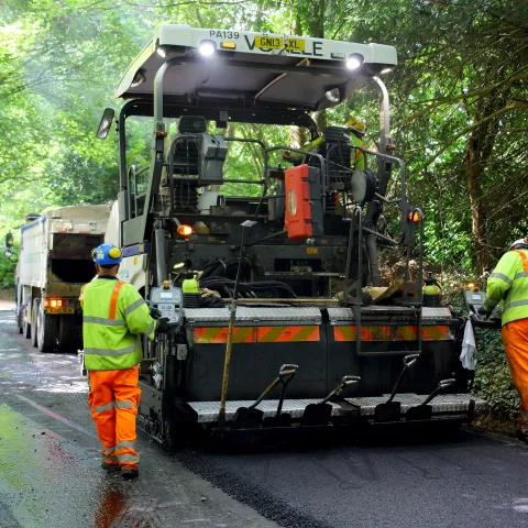 Workers spreading asphalt onto a forest road