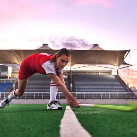 Female Hockey player hitting a ball across a hockey pitch
