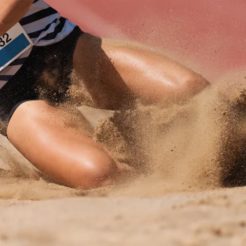 Athlete landing into jump pit sand