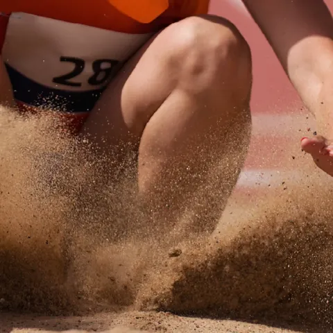 Sand sprinkles away as an athlete lands